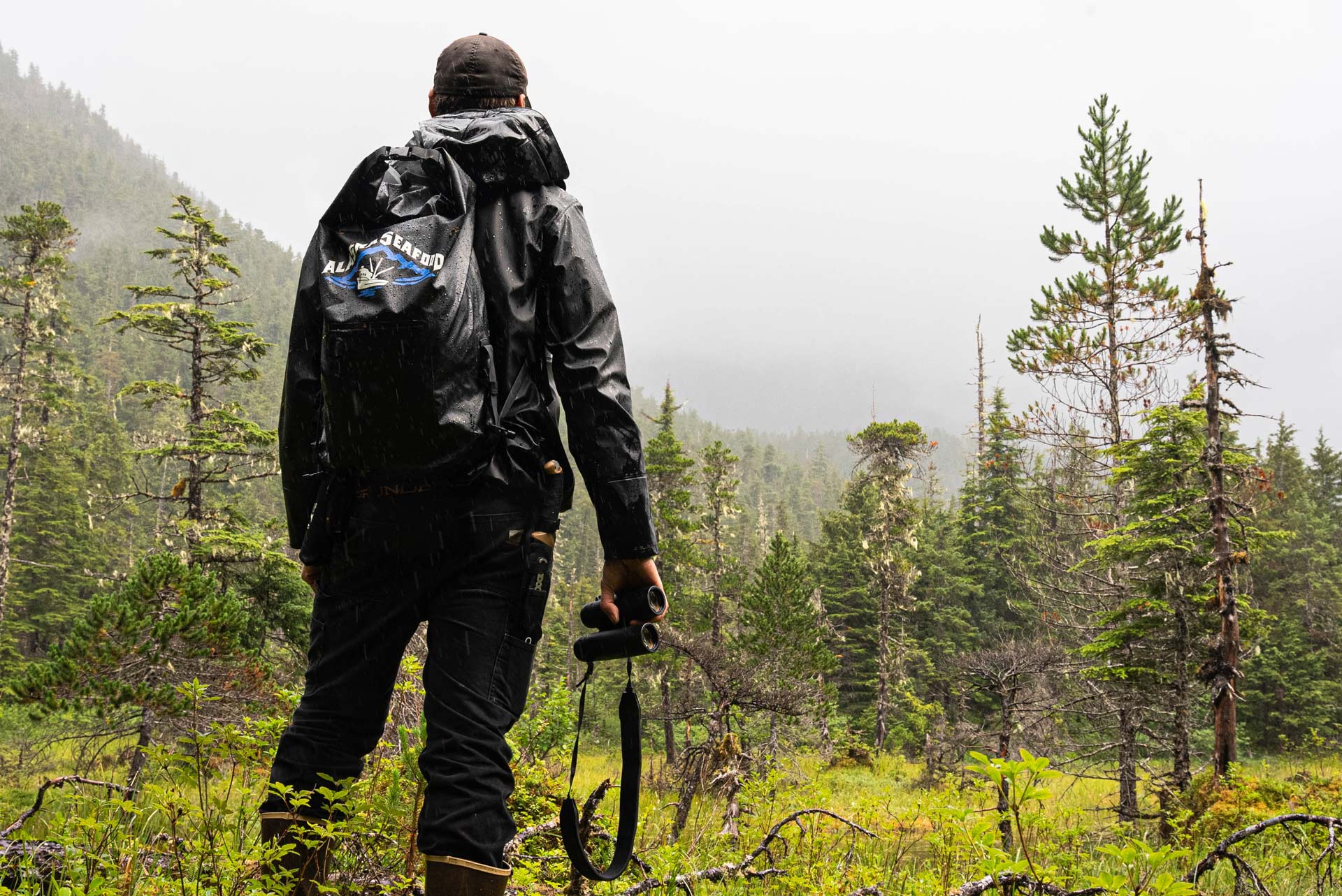 Man overlooking mountains with binoculars in hand during a mountain hunt