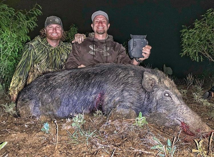 men posing with boar shot with hunting guide