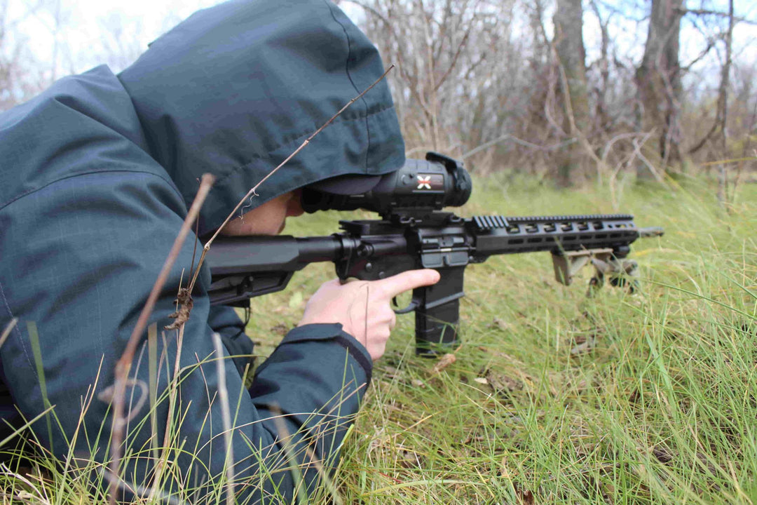 Man looking through hunting scope in grass