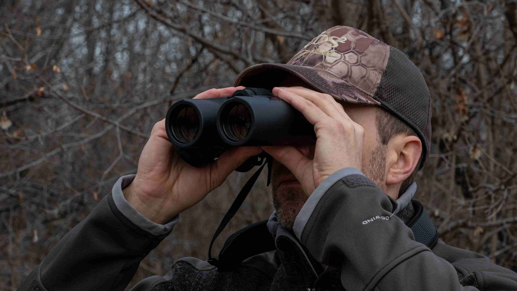 man looking through rangefinding binoculars